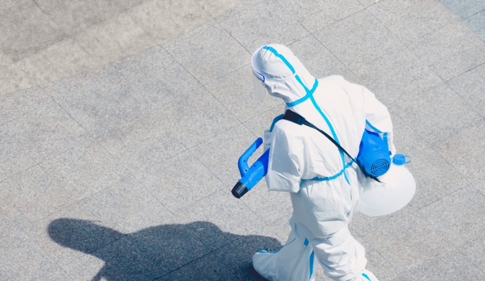 Protective-suit worker carrying sanitization equipment